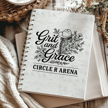 Notebook with 'Grit and Grace Circle R Arena' design on a textured surface.